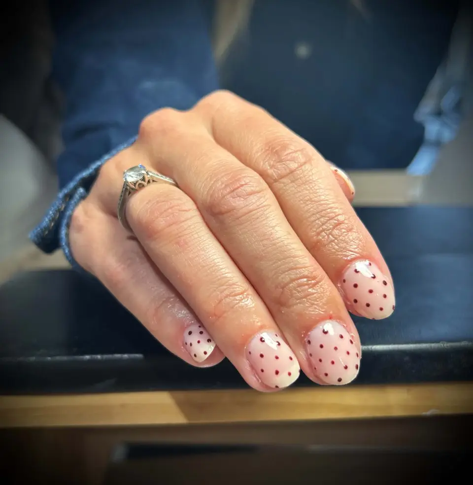 Pose de vernis rose poudré avec motif pois délicat